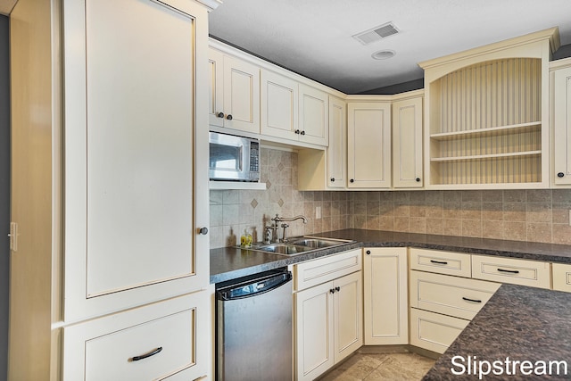 kitchen with dishwashing machine, cream cabinetry, stainless steel microwave, and dark countertops