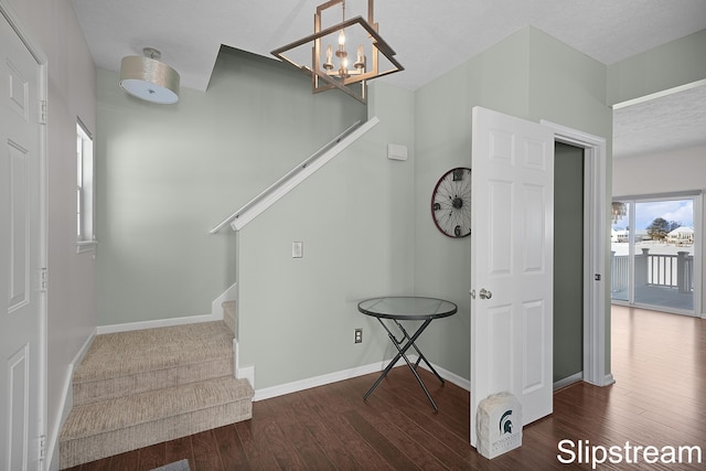 staircase featuring a chandelier, wood finished floors, and baseboards