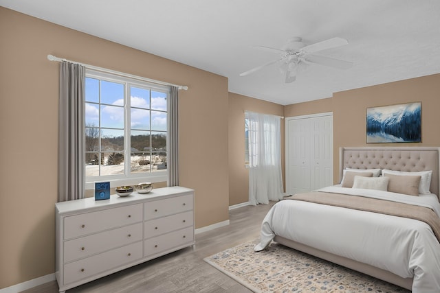 bedroom featuring a ceiling fan, light wood-style flooring, baseboards, and a closet