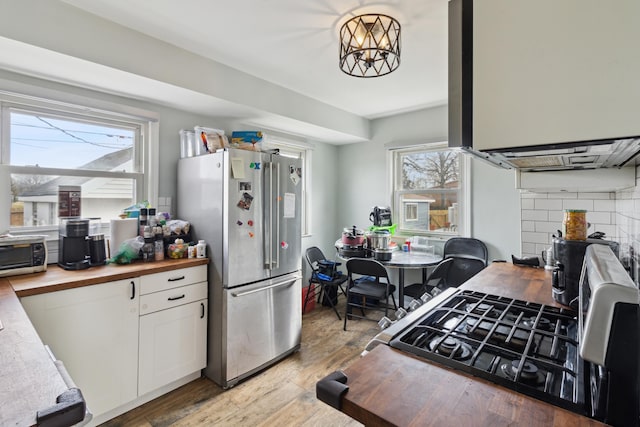 kitchen featuring light wood finished floors, a toaster, white cabinets, butcher block counters, and freestanding refrigerator