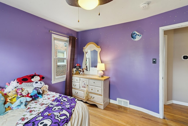 bedroom with ceiling fan, light wood-type flooring, visible vents, and baseboards