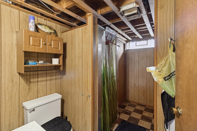 bathroom with wood walls, toilet, and tile patterned floors