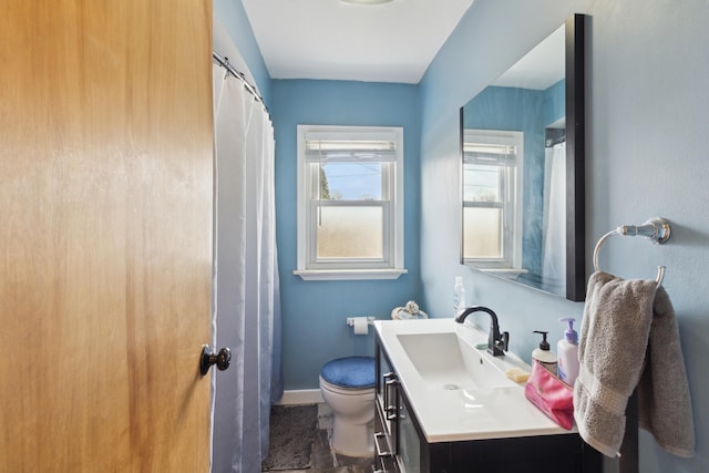 full bath with baseboards, vanity, and toilet