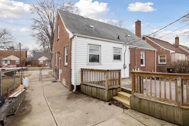 back of property featuring a chimney, a shingled roof, a gate, fence, and a deck