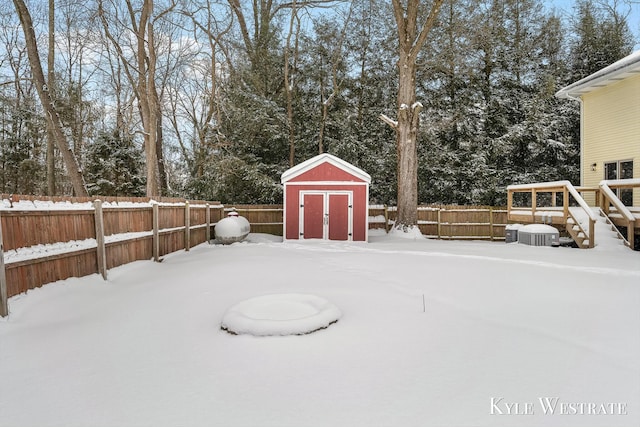 yard layered in snow featuring a fenced backyard, a storage unit, and an outdoor structure