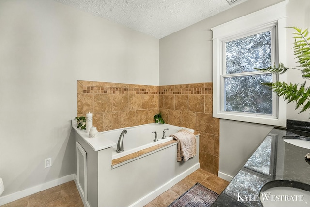 bathroom with a sink, a textured ceiling, baseboards, and a bath