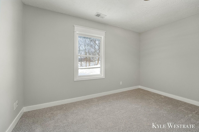 carpeted spare room with a textured ceiling, visible vents, and baseboards