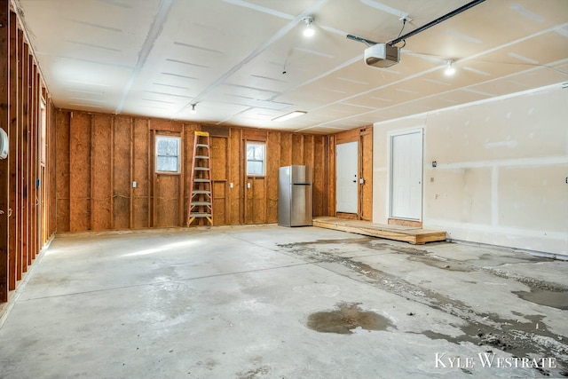 garage featuring freestanding refrigerator and a garage door opener