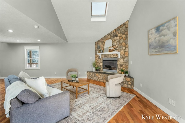 living room with baseboards, lofted ceiling with skylight, wood finished floors, a fireplace, and recessed lighting