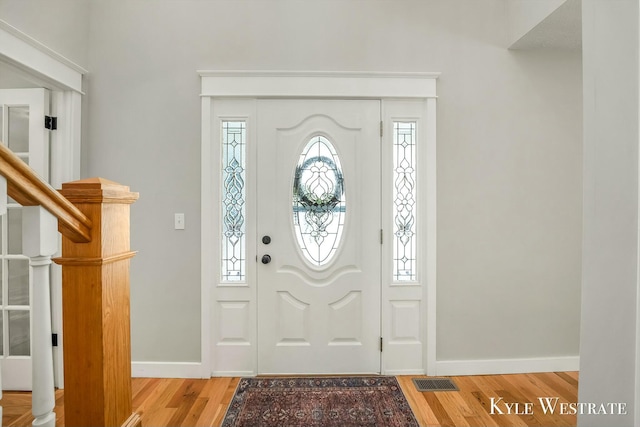 foyer entrance featuring stairs, visible vents, baseboards, and wood finished floors