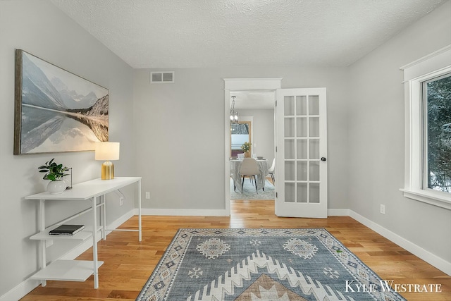 living area with a wealth of natural light, wood finished floors, visible vents, and baseboards