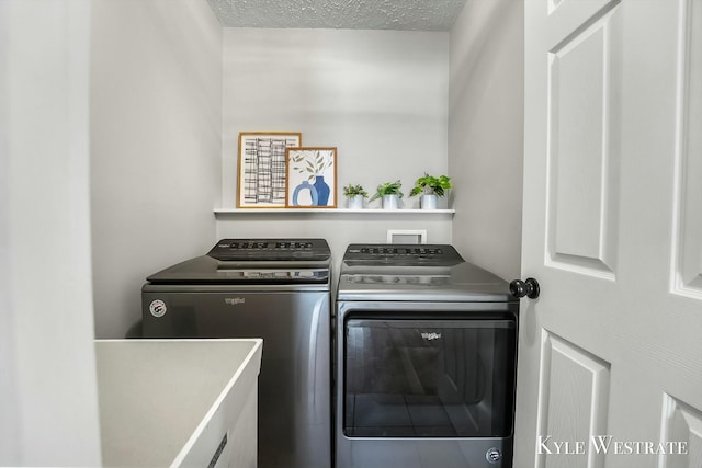 clothes washing area with laundry area, a textured ceiling, and washing machine and clothes dryer