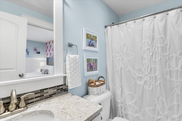 bathroom featuring tasteful backsplash, vanity, and toilet