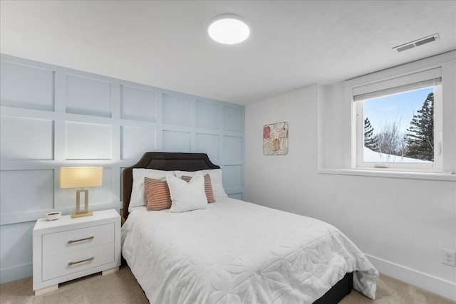 bedroom featuring light carpet, baseboards, visible vents, and a decorative wall