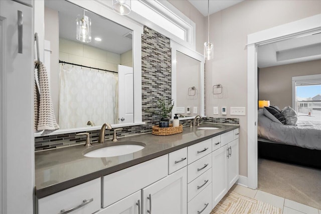 ensuite bathroom featuring double vanity, tasteful backsplash, a sink, and ensuite bathroom