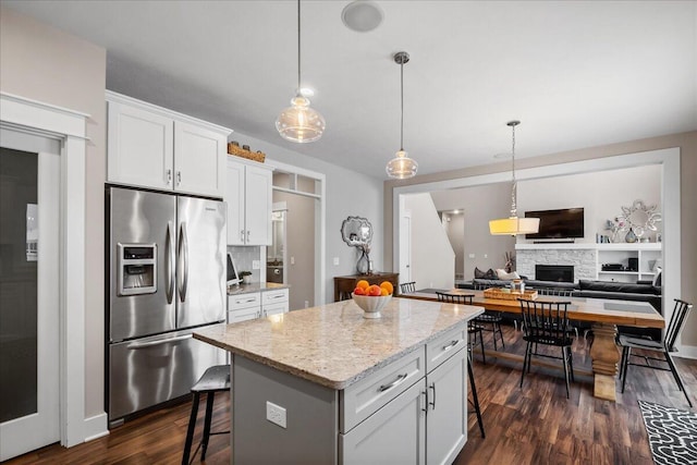 kitchen with a center island, stainless steel fridge with ice dispenser, open floor plan, white cabinetry, and a kitchen breakfast bar