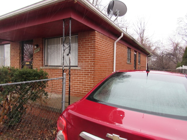 view of side of home featuring fence and brick siding