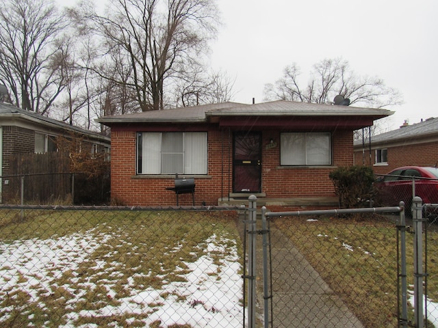 bungalow-style home with a fenced front yard, a gate, brick siding, and a lawn