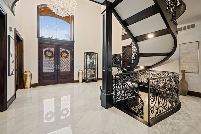 foyer entrance with visible vents, a towering ceiling, stairway, french doors, and a notable chandelier