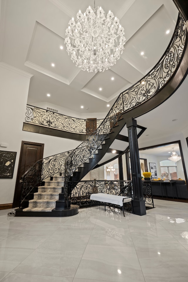 stairs with decorative columns, visible vents, ornamental molding, an inviting chandelier, and a high ceiling