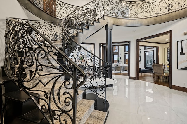 stairs with ornate columns, crown molding, and baseboards