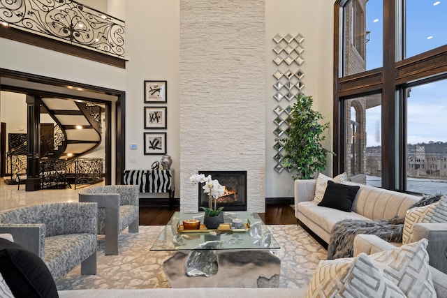 living area featuring baseboards, a fireplace, a high ceiling, and wood finished floors