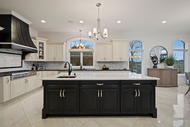 kitchen featuring a sink, a wealth of natural light, a center island with sink, and dark cabinets