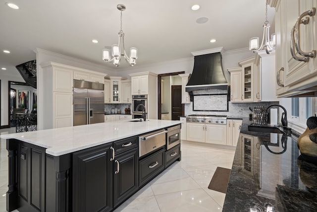 kitchen featuring a notable chandelier, dark cabinets, stainless steel appliances, premium range hood, and a warming drawer