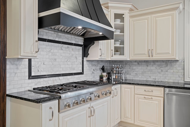 kitchen featuring glass insert cabinets, custom range hood, stainless steel gas cooktop, and backsplash