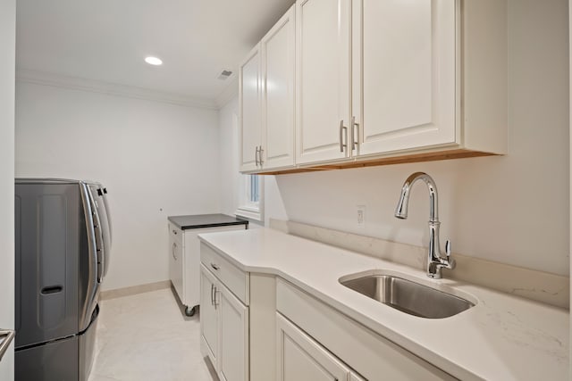 kitchen with visible vents, white cabinets, ornamental molding, light countertops, and a sink