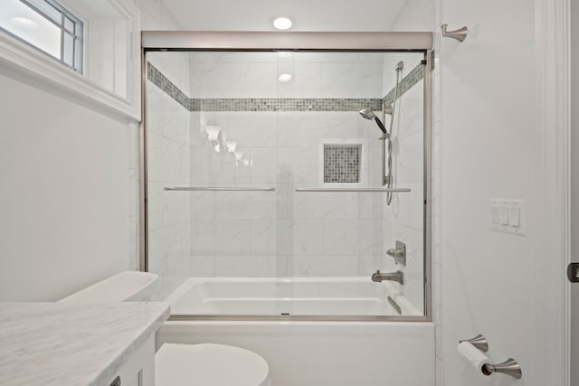 bathroom with shower / bath combination with glass door, vanity, and toilet