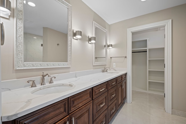 bathroom featuring double vanity, a sink, and a walk in closet