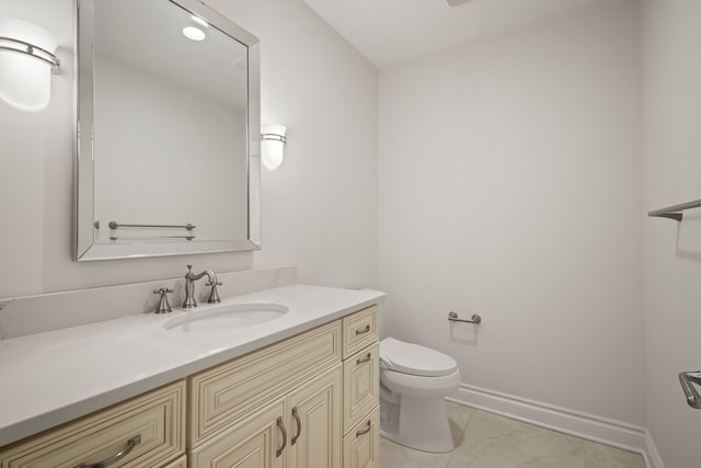 bathroom featuring toilet, baseboards, and vanity