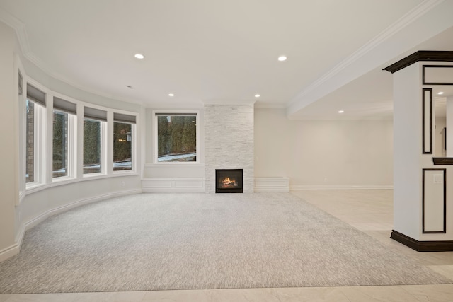 unfurnished living room featuring carpet floors, ornamental molding, recessed lighting, and a stone fireplace