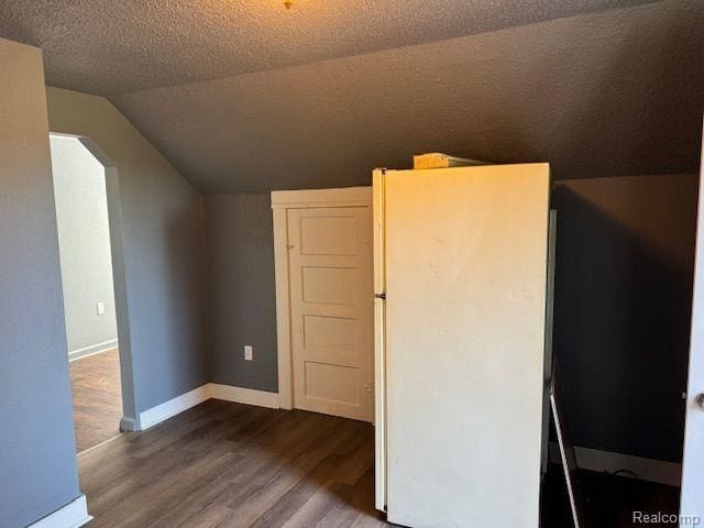 bonus room featuring arched walkways, a textured ceiling, lofted ceiling, wood finished floors, and baseboards