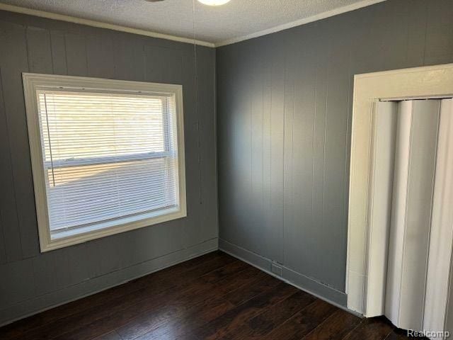 spare room featuring a ceiling fan, dark wood-style flooring, crown molding, and a textured ceiling