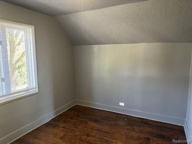 bonus room with vaulted ceiling, a textured ceiling, dark wood finished floors, and baseboards