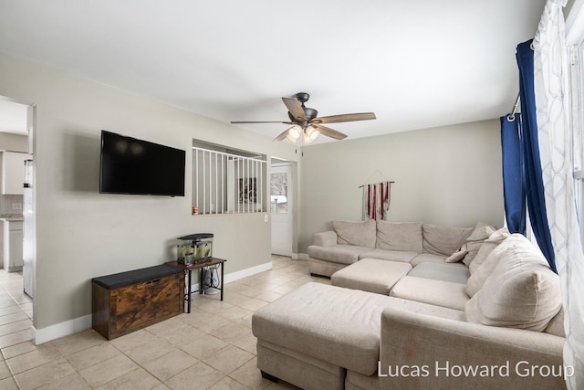 living area featuring light tile patterned floors, a ceiling fan, and baseboards