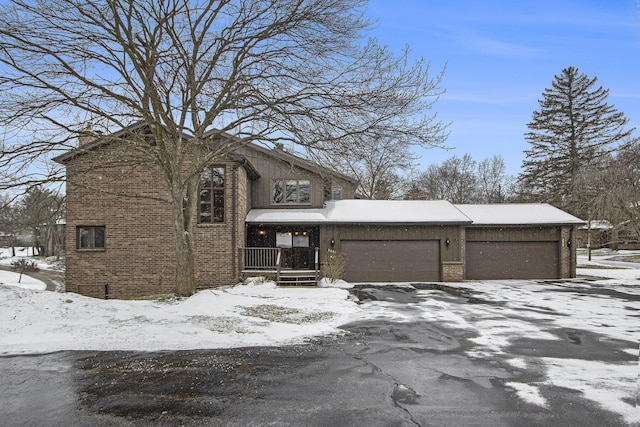 view of front of home featuring covered porch, brick siding, a chimney, and an attached garage