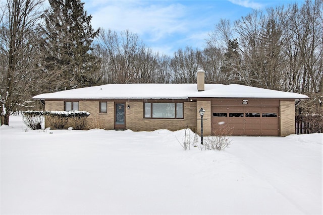 ranch-style home with an attached garage, a chimney, and brick siding