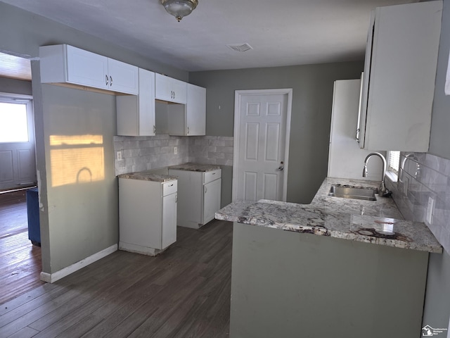 kitchen featuring backsplash, a sink, dark wood finished floors, and white cabinets