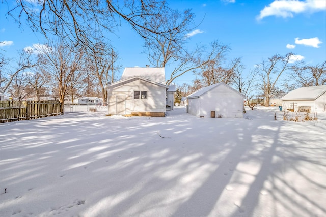 snow covered property featuring fence and an outdoor structure