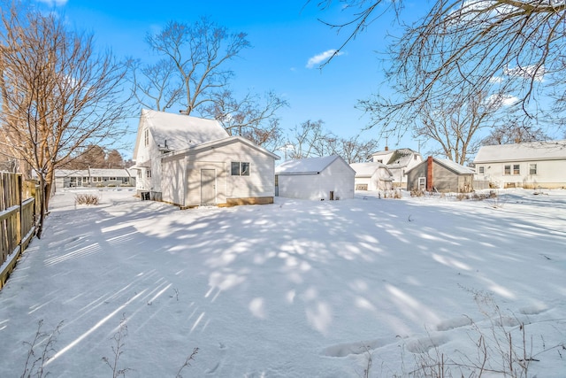 snow covered property with an outbuilding, a residential view, and fence