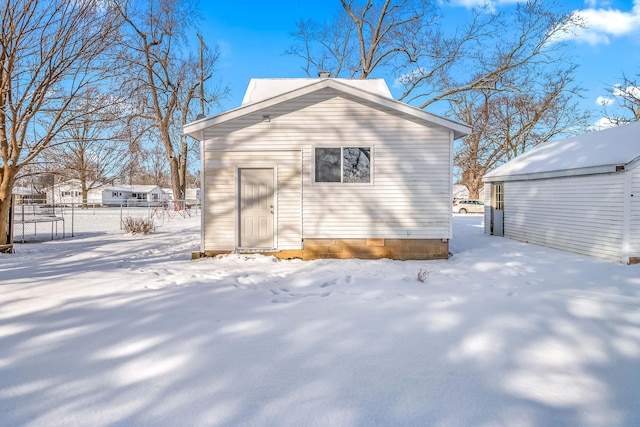 snow covered structure with an outdoor structure and fence