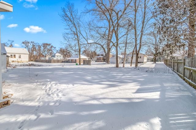 snowy yard with a residential view and fence