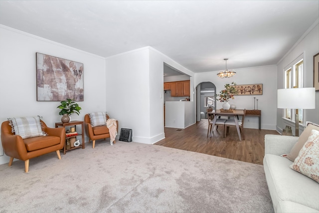 living room featuring baseboards, arched walkways, crown molding, dark carpet, and a notable chandelier