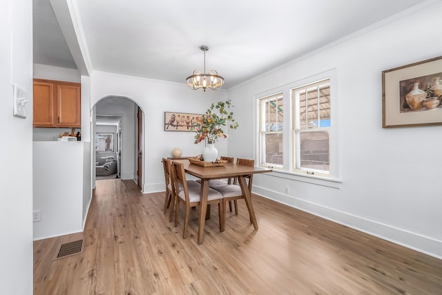 dining area featuring light wood finished floors, baseboards, arched walkways, and a notable chandelier