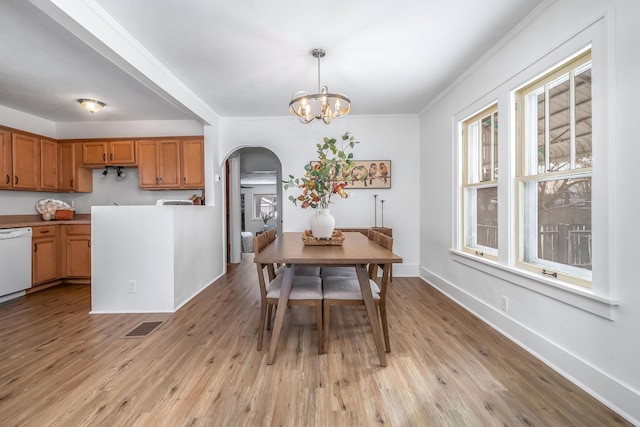 dining space with arched walkways, visible vents, a notable chandelier, and light wood finished floors