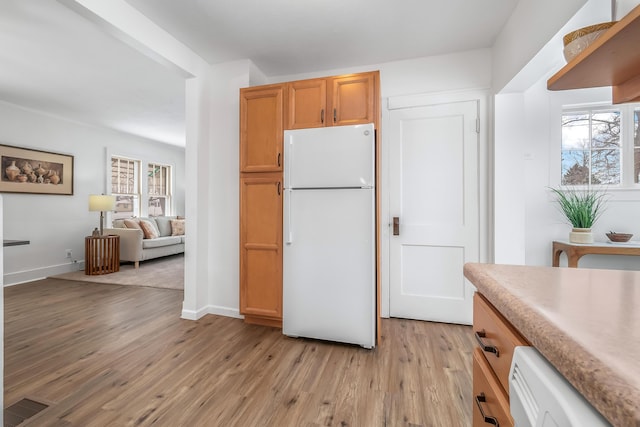 kitchen with light countertops, a wealth of natural light, light wood-style flooring, and freestanding refrigerator