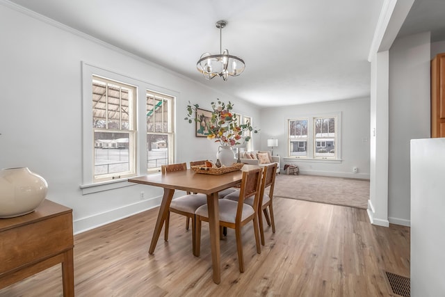 dining area featuring baseboards, light wood-type flooring, visible vents, and a notable chandelier